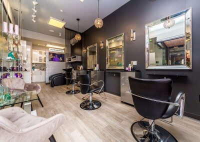 Modern hair salon with stylish decor, comfortable seating, and well-lit workstations.